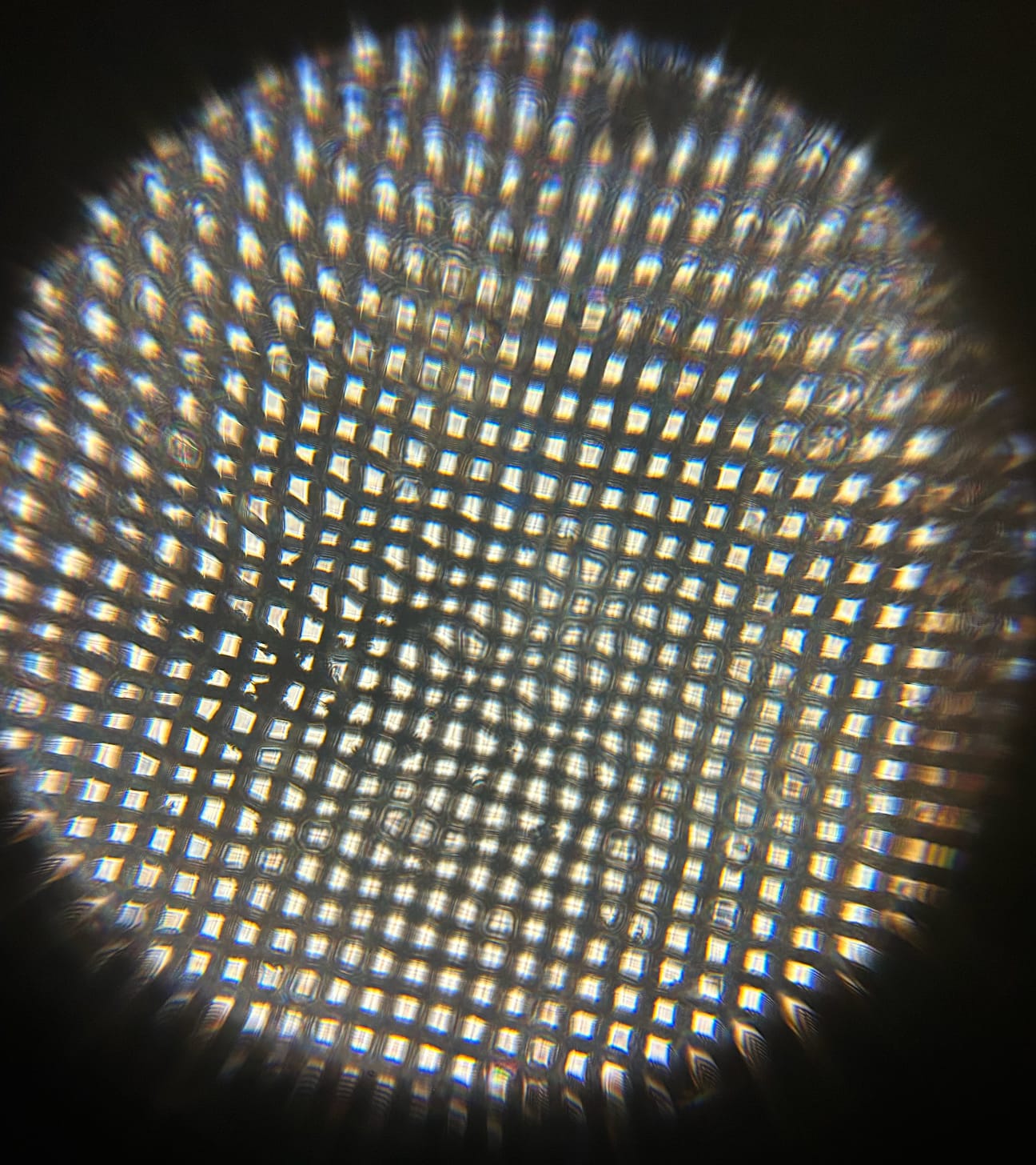 Seen through a Foldscope, a stainless-steel mesh appears as a glowing grid of square pores