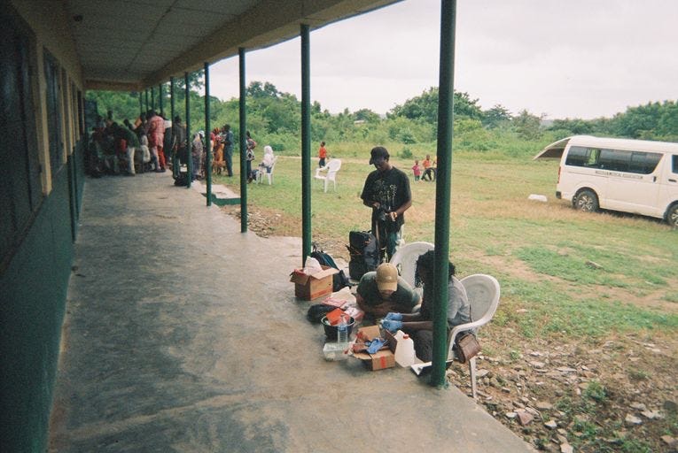 Researchers in gloves cleaning and sorting snails on a tray while community members gather in the background